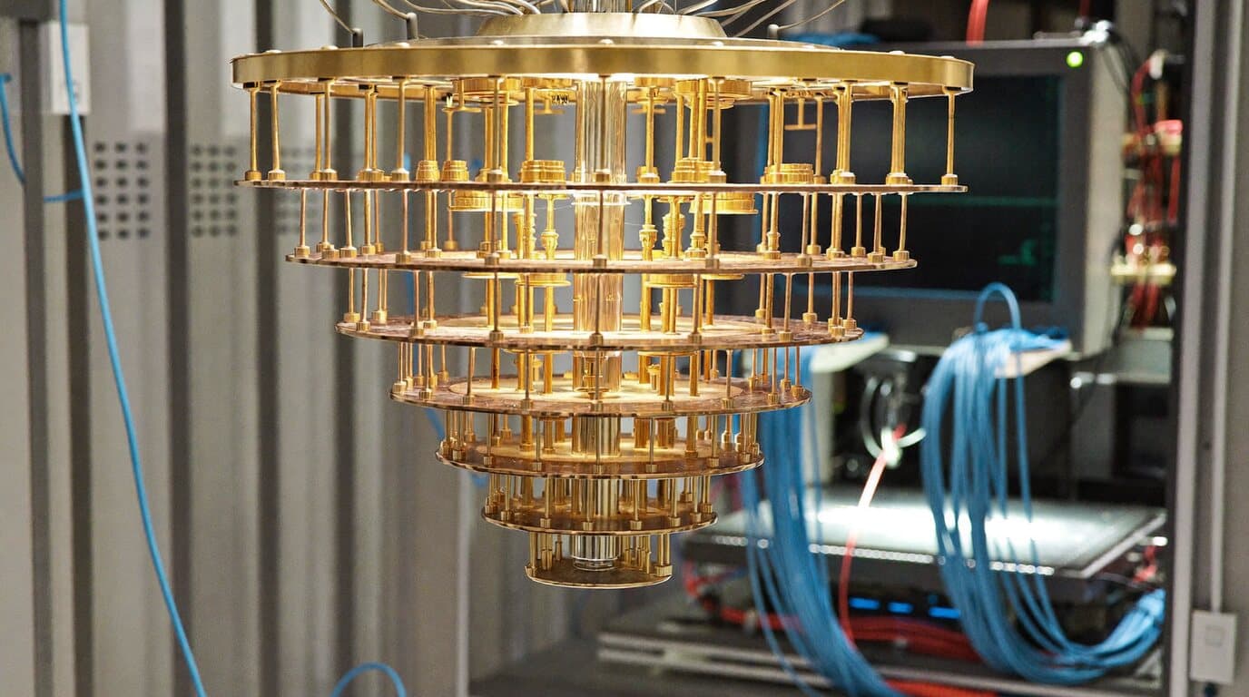 Cryostat of a superconducting quantum computer, with its tiered gold structure and blue coaxial cabling.