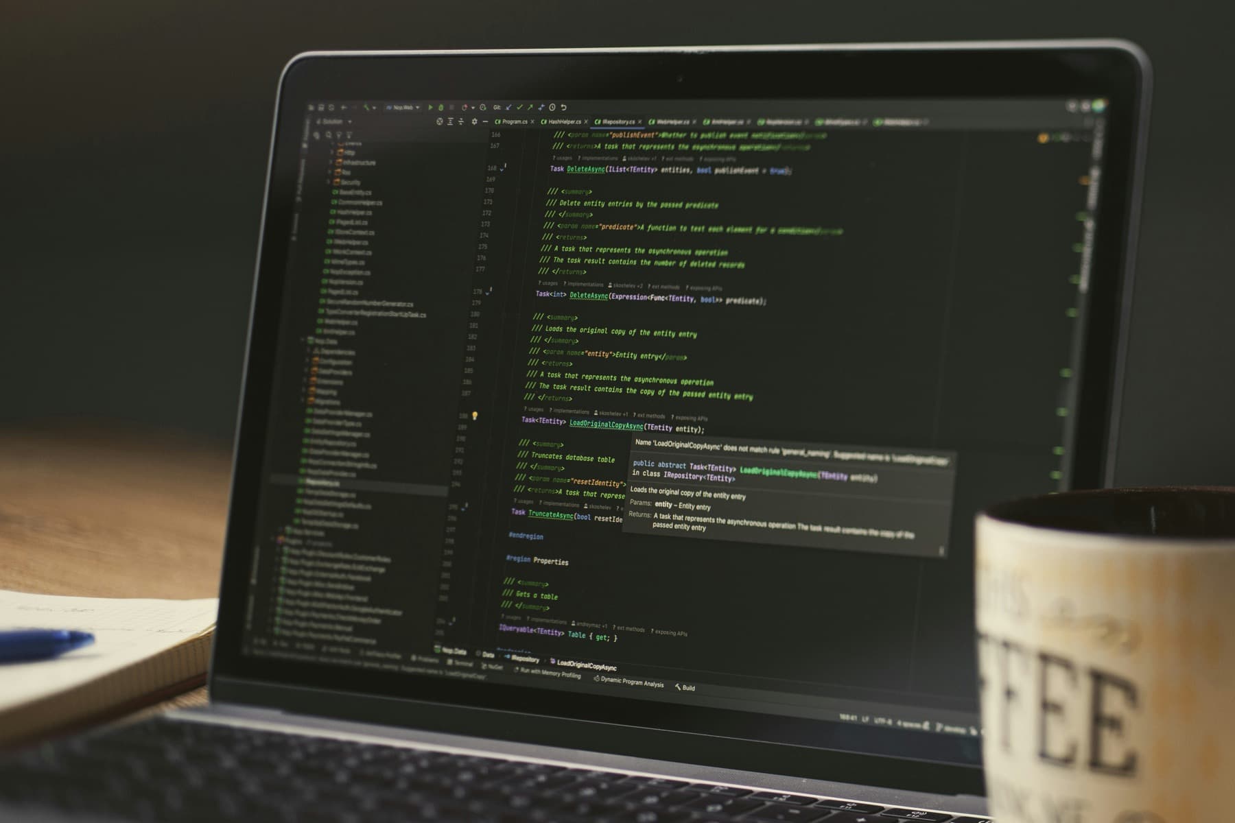 Laptop screen with code and a coffee cup on a work desk